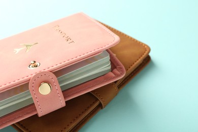 Photo of Two passports in bright covers on turquoise background, closeup