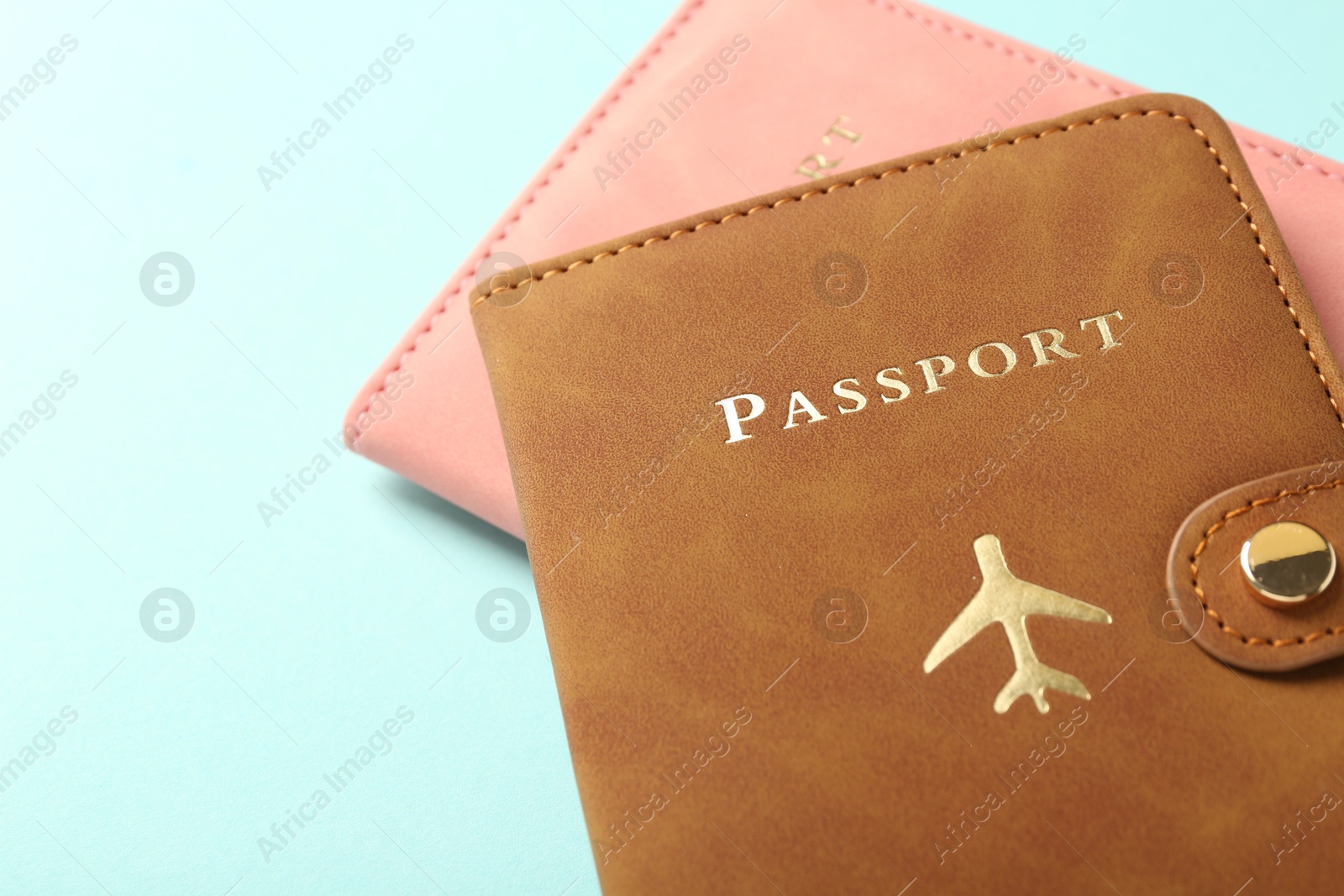 Photo of Two passports in bright covers on turquoise background, closeup