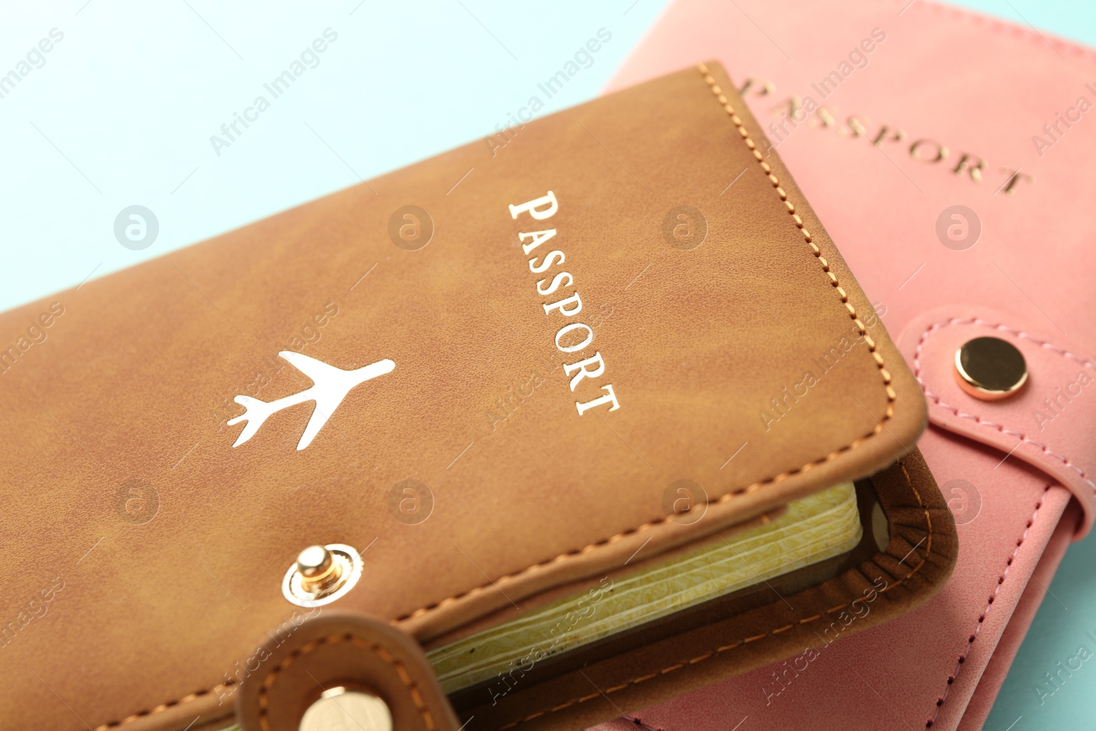 Photo of Two passports in bright covers on turquoise background, closeup