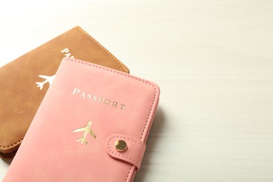 Photo of Two passports in bright covers on white wooden table, closeup. Space for text