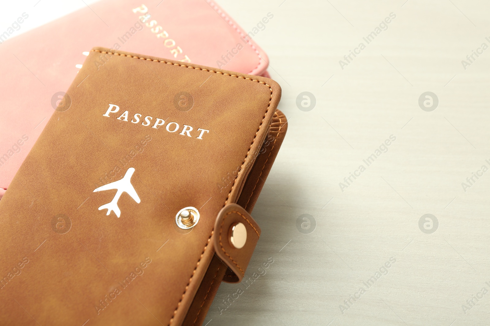 Photo of Two passports in bright covers on white wooden table, closeup. Space for text