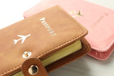 Photo of Two passports in bright covers on white wooden table, closeup