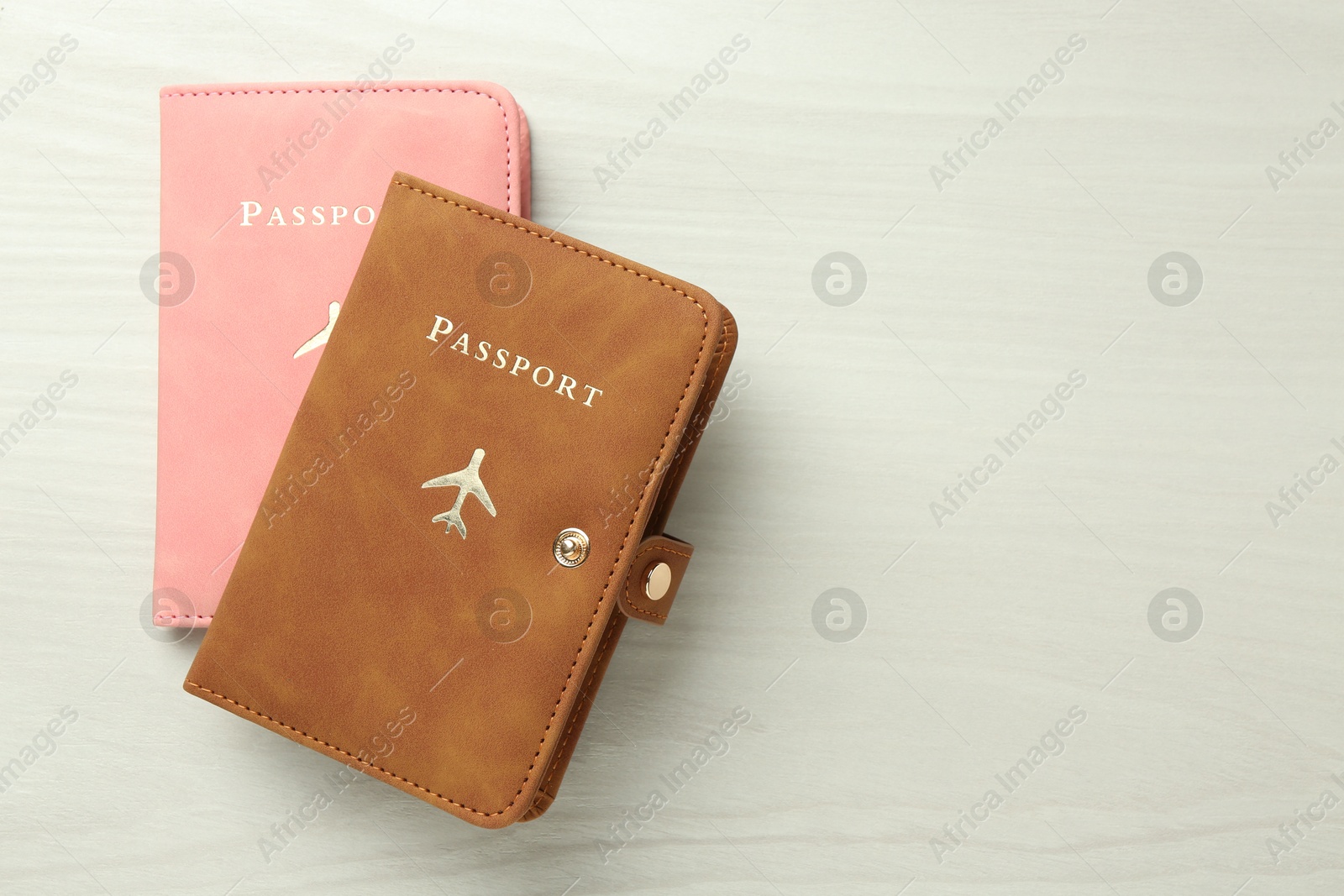 Photo of Two passports in bright covers on white wooden table, top view. Space for text