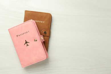 Photo of Two passports in bright covers on white wooden table, top view. Space for text