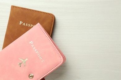 Photo of Two passports in bright covers on white wooden table, top view. Space for text