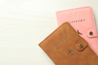 Photo of Two passports in bright covers on white wooden table, top view. Space for text