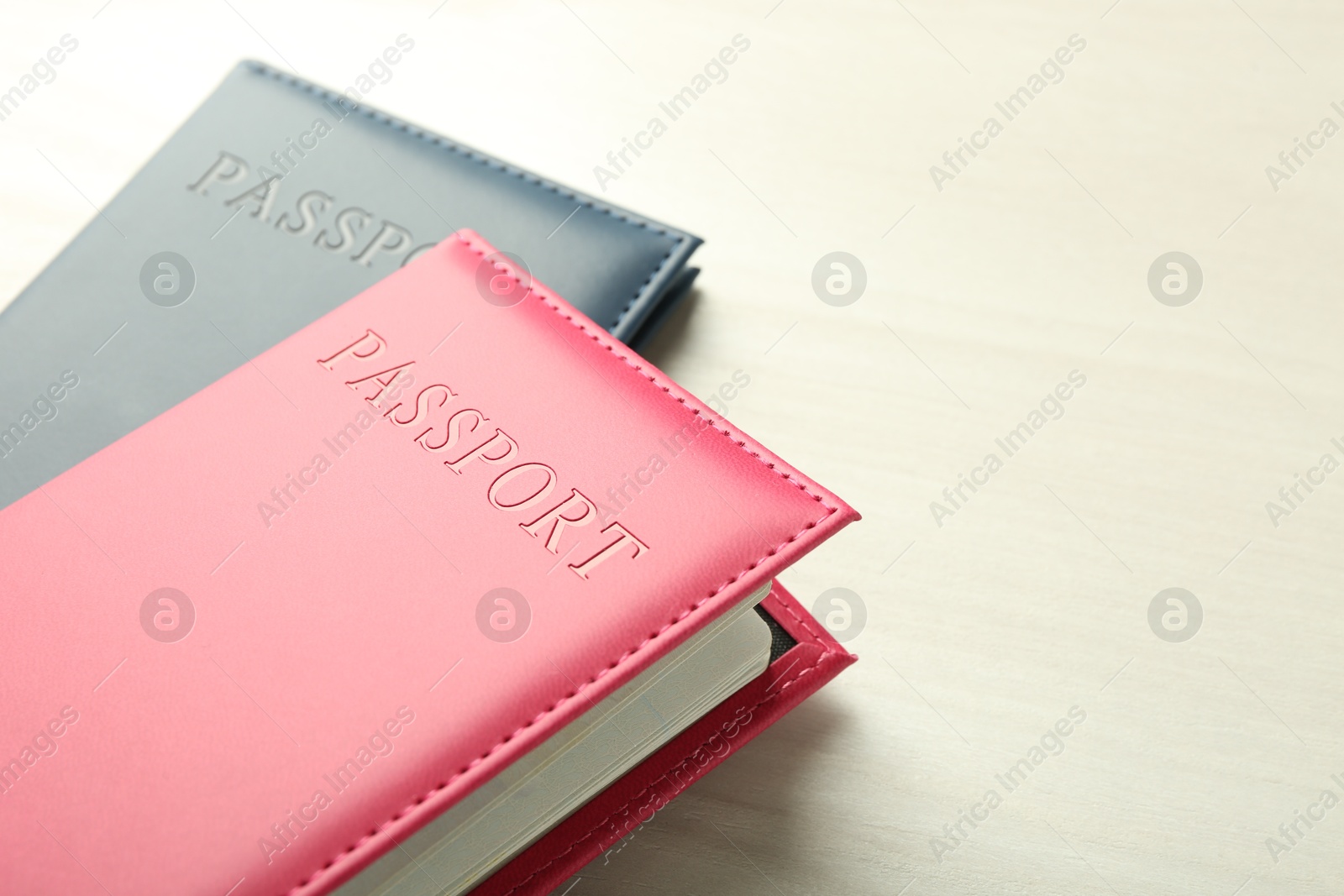 Photo of Two passports in bright covers on white wooden table, closeup