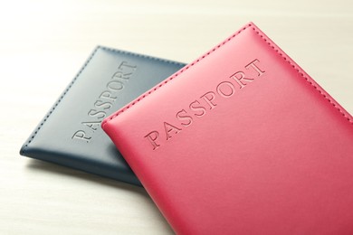 Photo of Two passports in bright covers on white wooden table, closeup