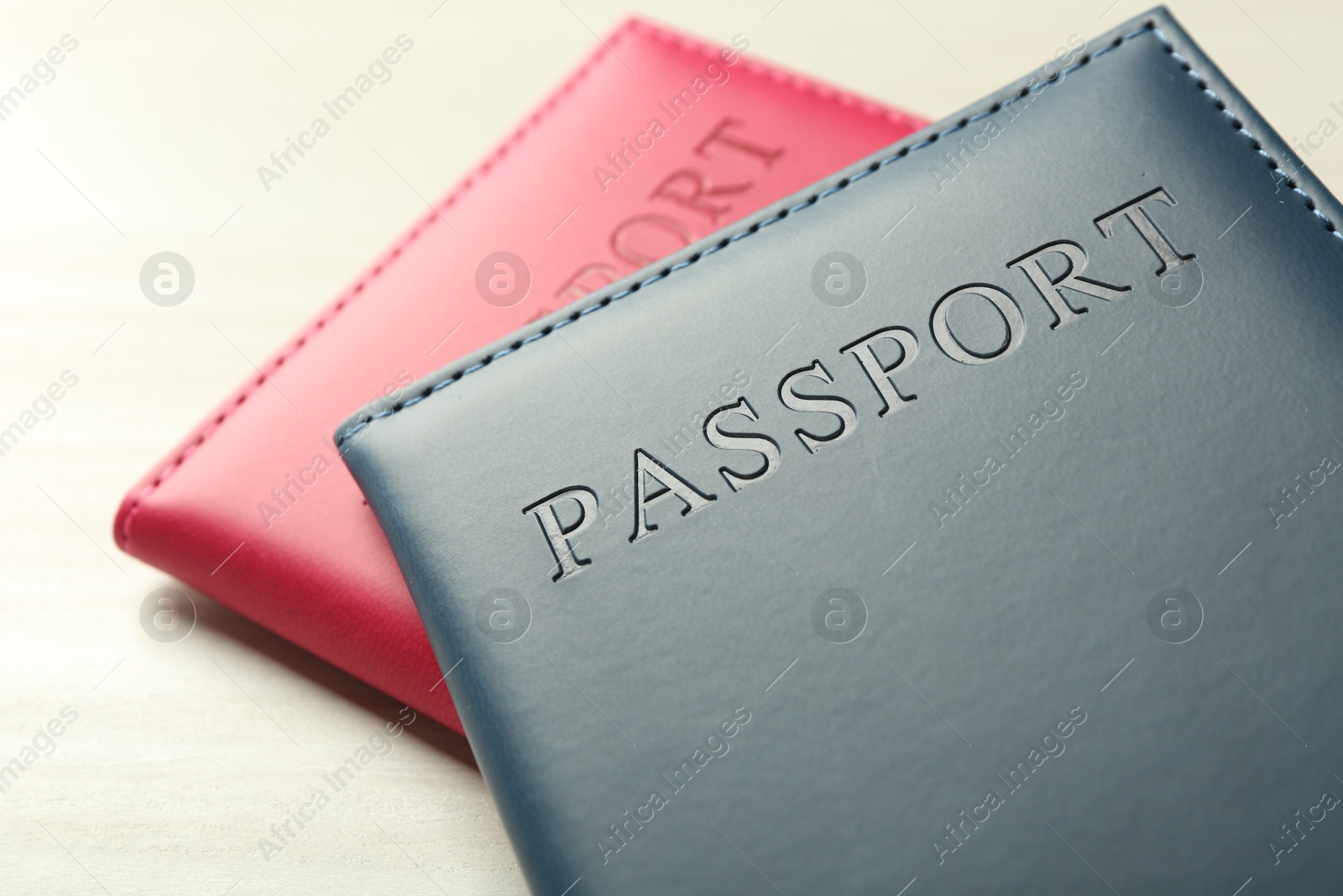 Photo of Two passports in bright covers on white wooden table, closeup