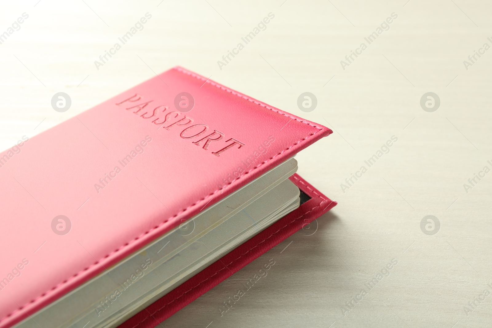 Photo of Passport in bright pink cover on white wooden table, closeup. Space for text