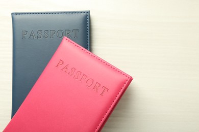 Photo of Two passports in bright covers on white wooden table, top view. Space for text