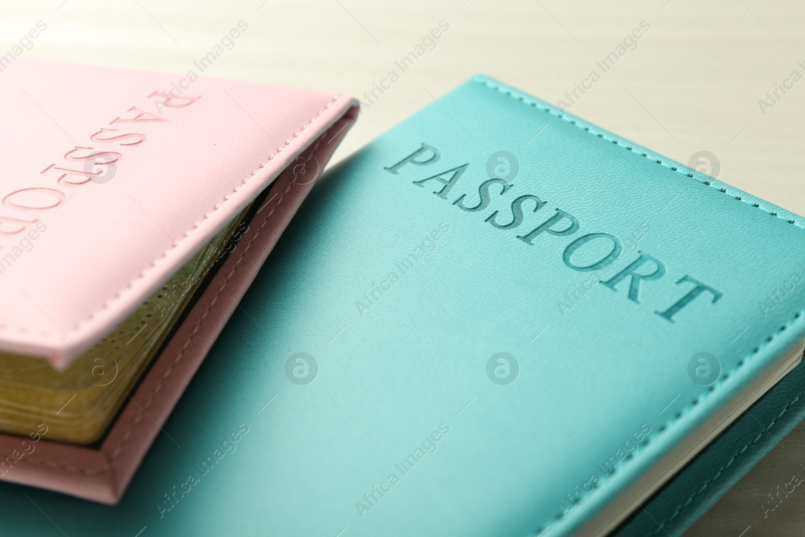 Photo of Two passports in bright covers on white wooden table, closeup