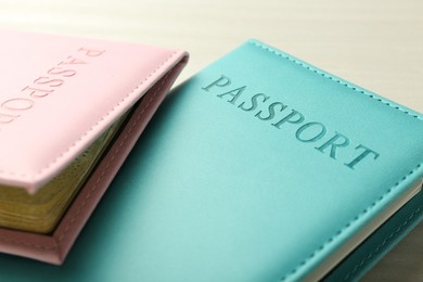 Photo of Two passports in bright covers on white wooden table, closeup