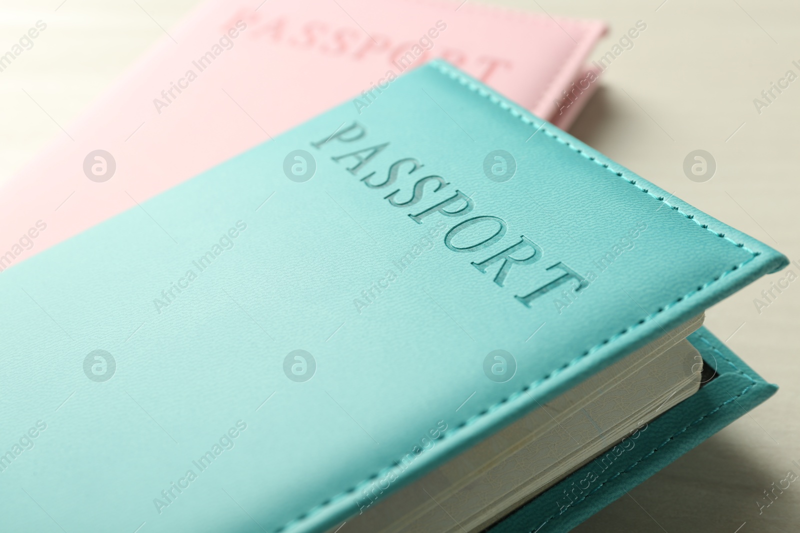 Photo of Two passports in bright covers on white wooden table, closeup