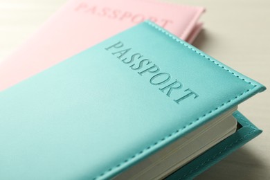 Photo of Two passports in bright covers on white wooden table, closeup