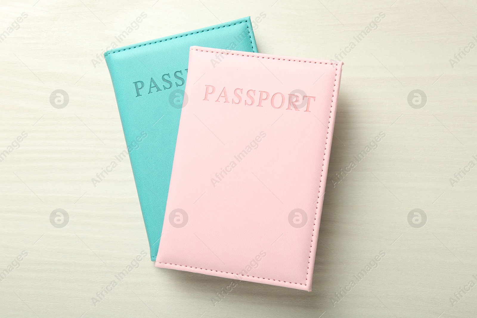 Photo of Two passports in bright covers on white wooden table, top view