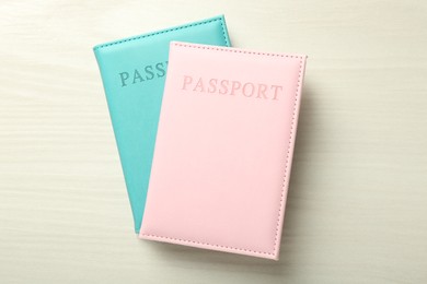 Photo of Two passports in bright covers on white wooden table, top view