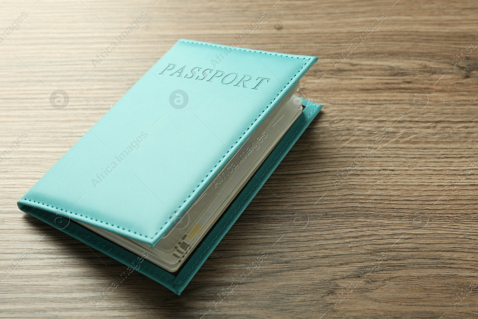 Photo of Passport in bright turquoise cover on wooden table, space for text