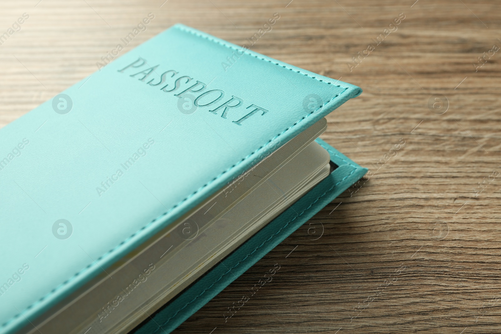 Photo of Passport in bright turquoise cover on wooden table, closeup