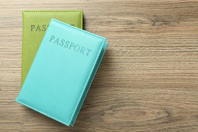 Photo of Two passports in bright covers on wooden table, top view. Space for text