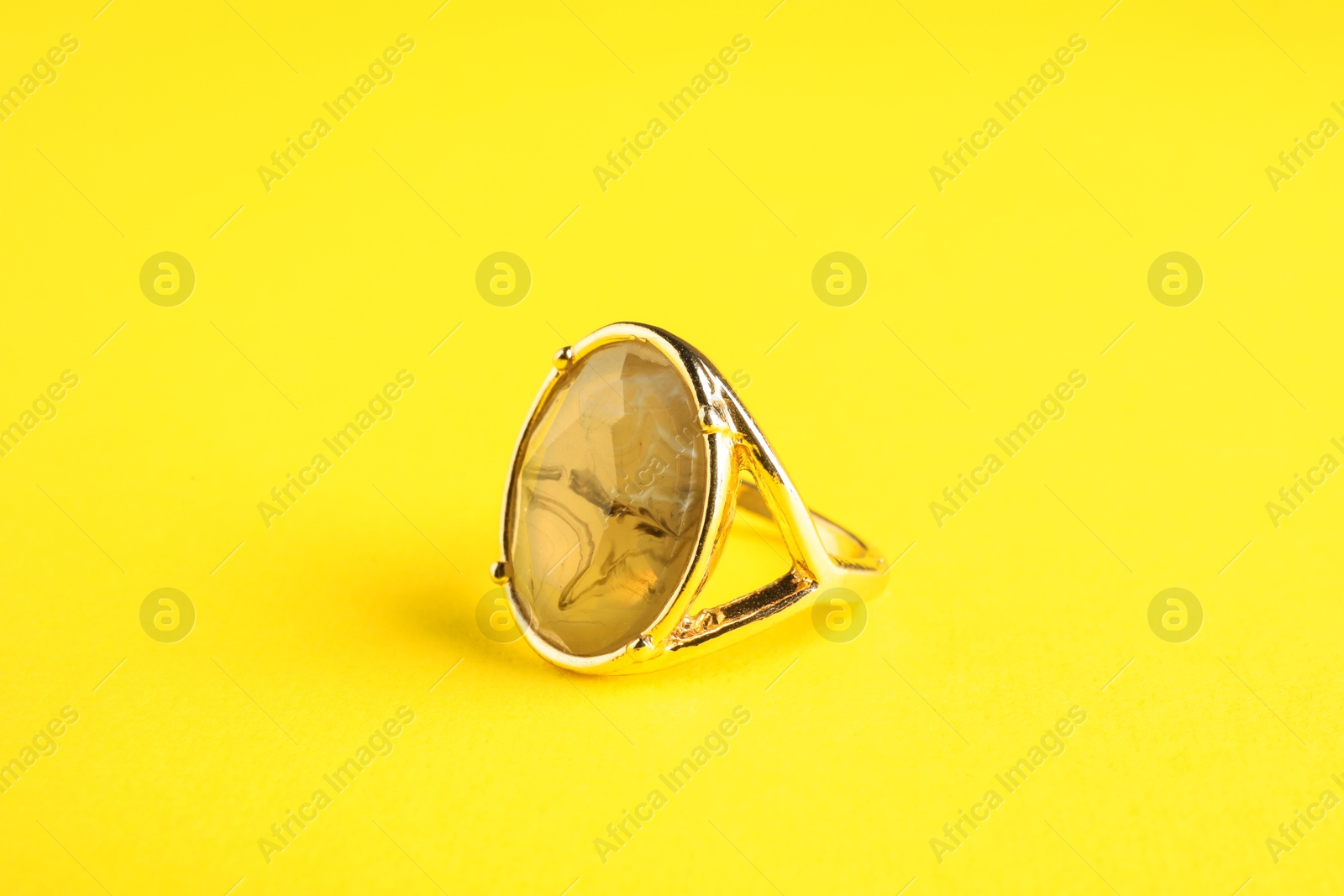 Photo of Beautiful bijouterie. Elegant ring on yellow background