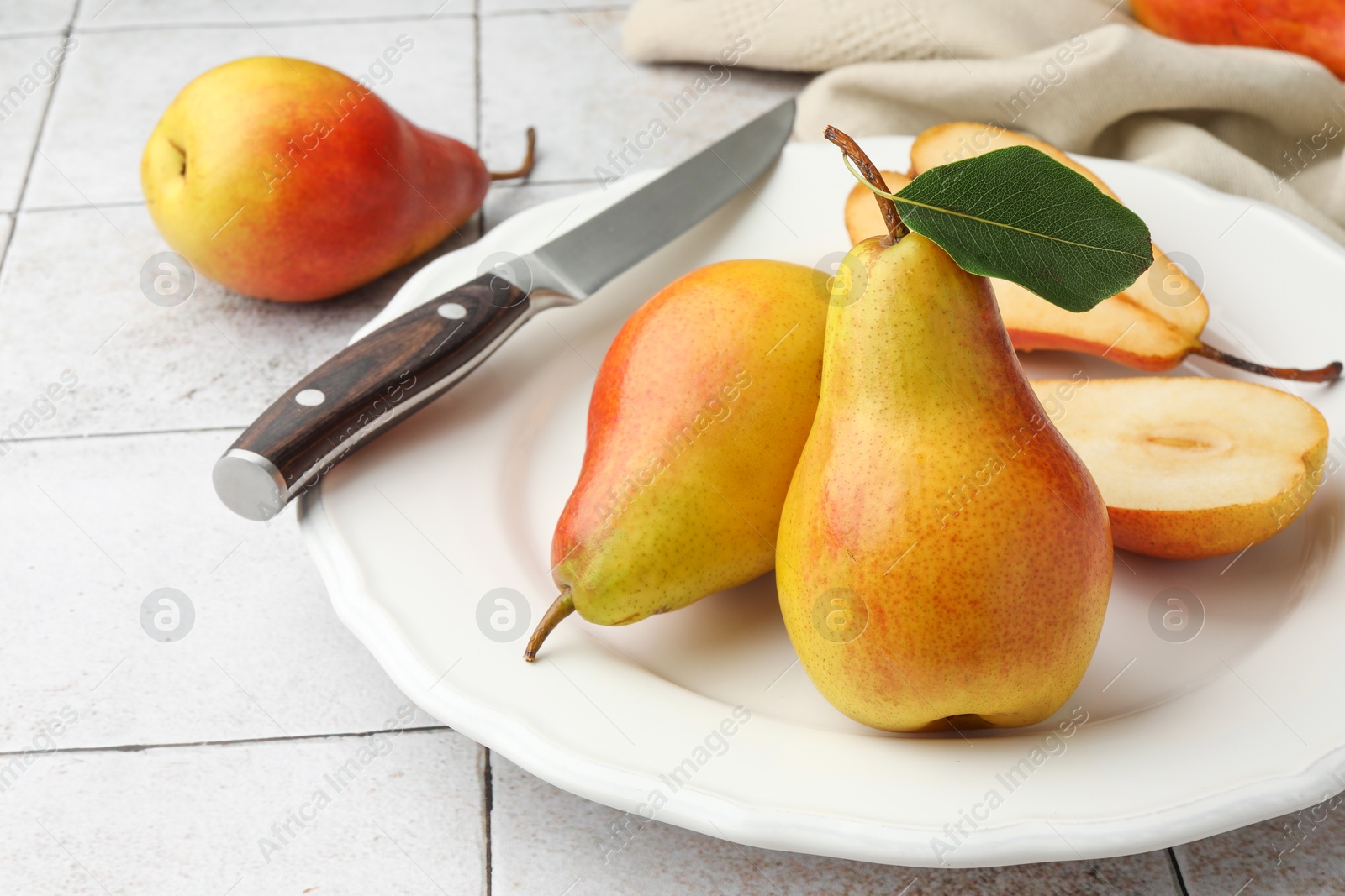 Photo of Ripe juicy pears on light tiled table, closeup