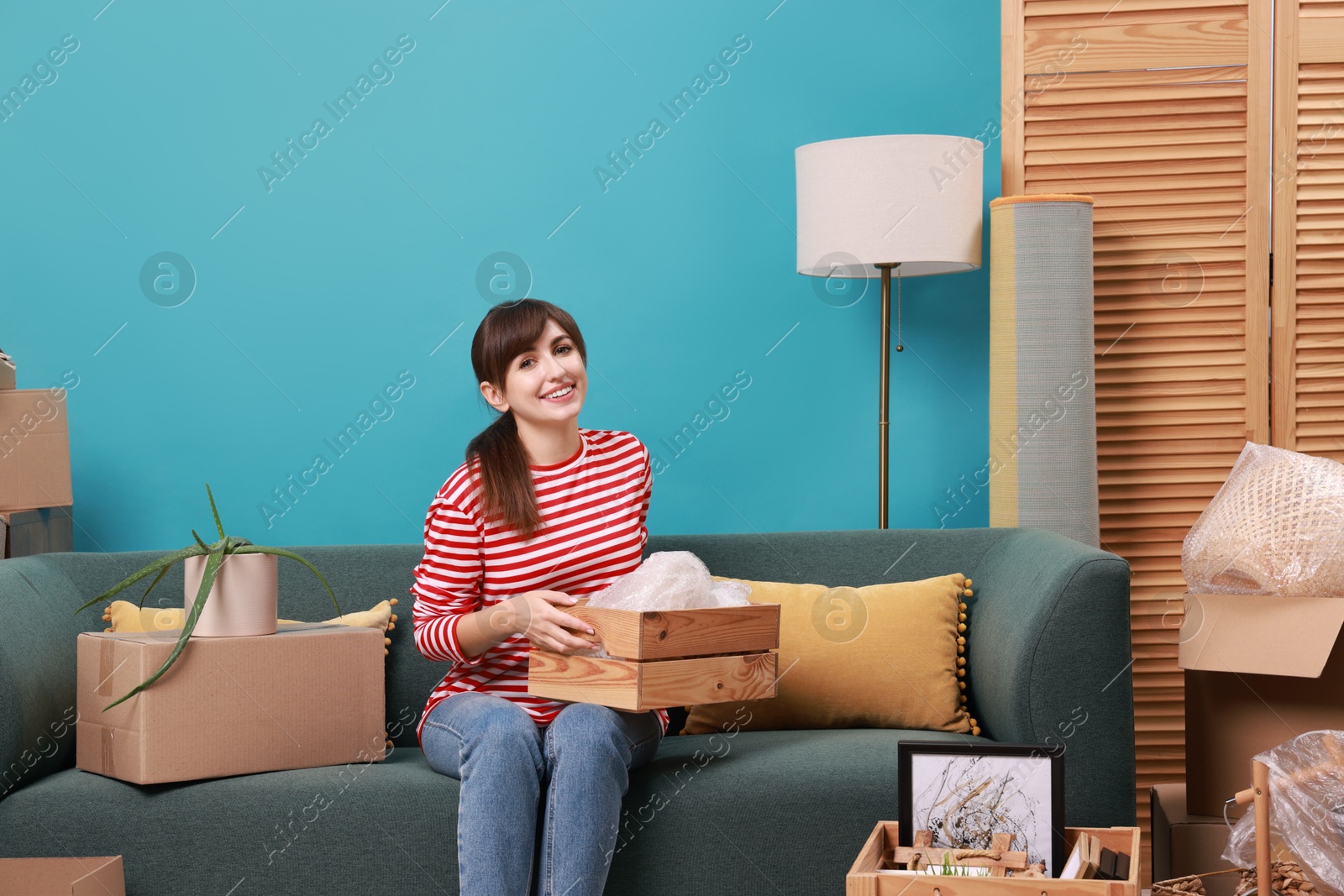 Photo of Happy woman with moving boxes in new apartment. Housewarming party