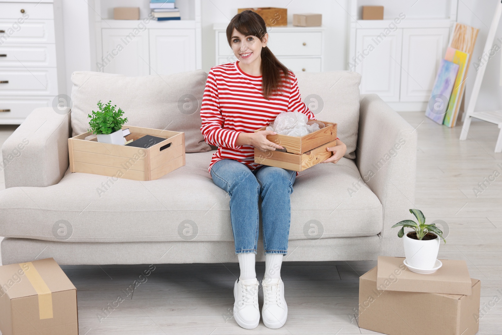 Photo of Happy woman with moving boxes in new apartment. Housewarming party