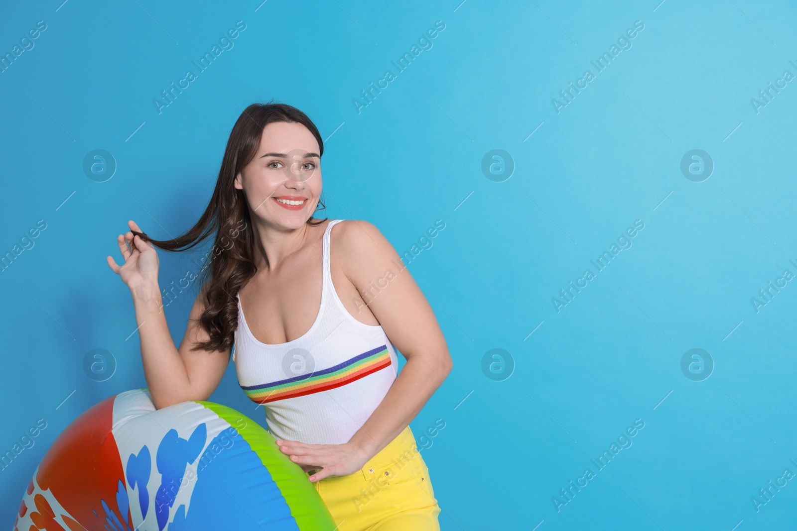 Photo of Beautiful woman in swimsuit with inflatable ring on light blue background. Space for text