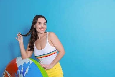 Photo of Beautiful woman in swimsuit with inflatable ring on light blue background. Space for text