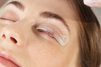 Photo of Eyelash lamination procedure. Woman with silicone pad on eyelid in beauty salon, closeup