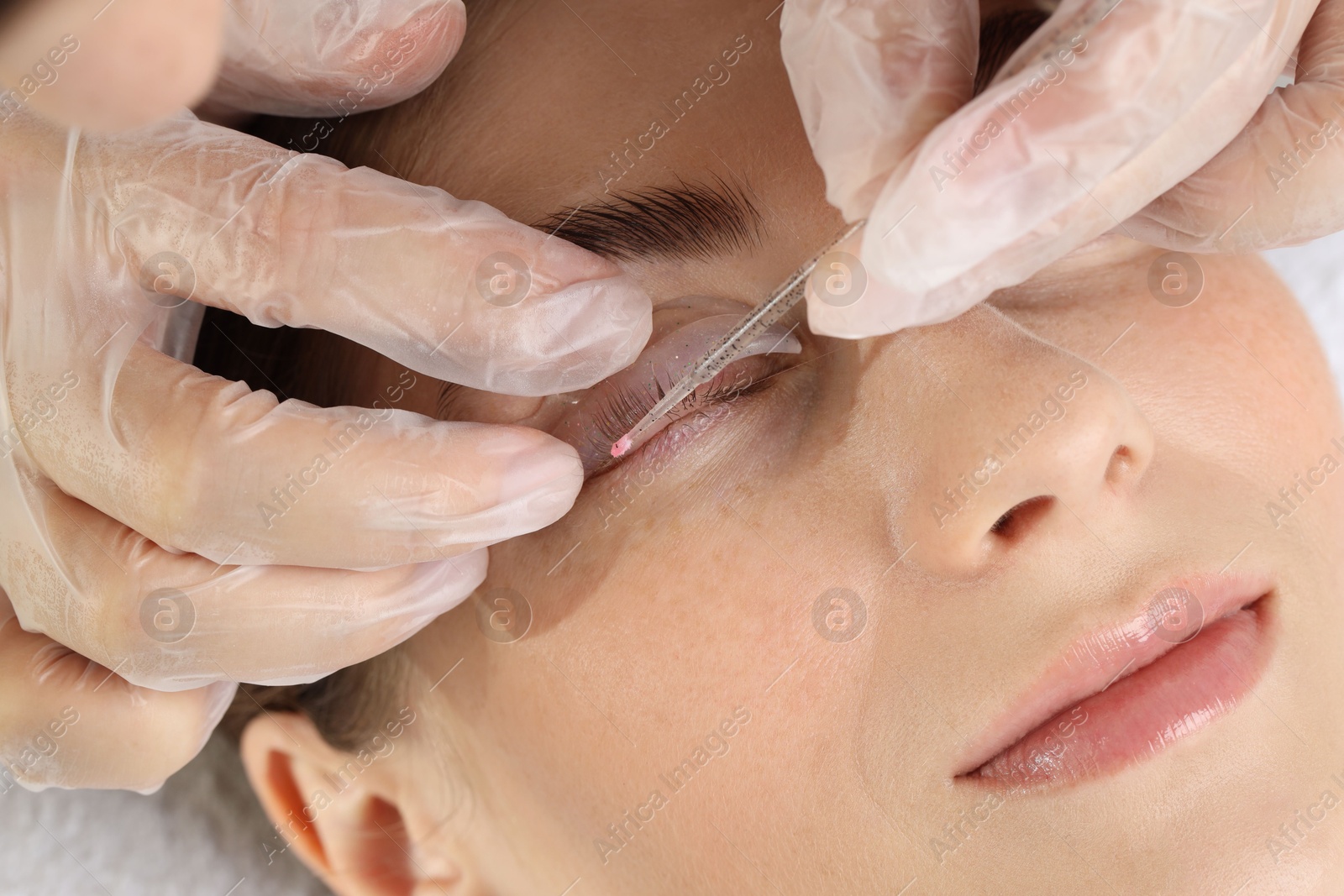 Photo of Eyelash lamination procedure. Esthetician sticking woman's lashes to pad in beauty salon, closeup