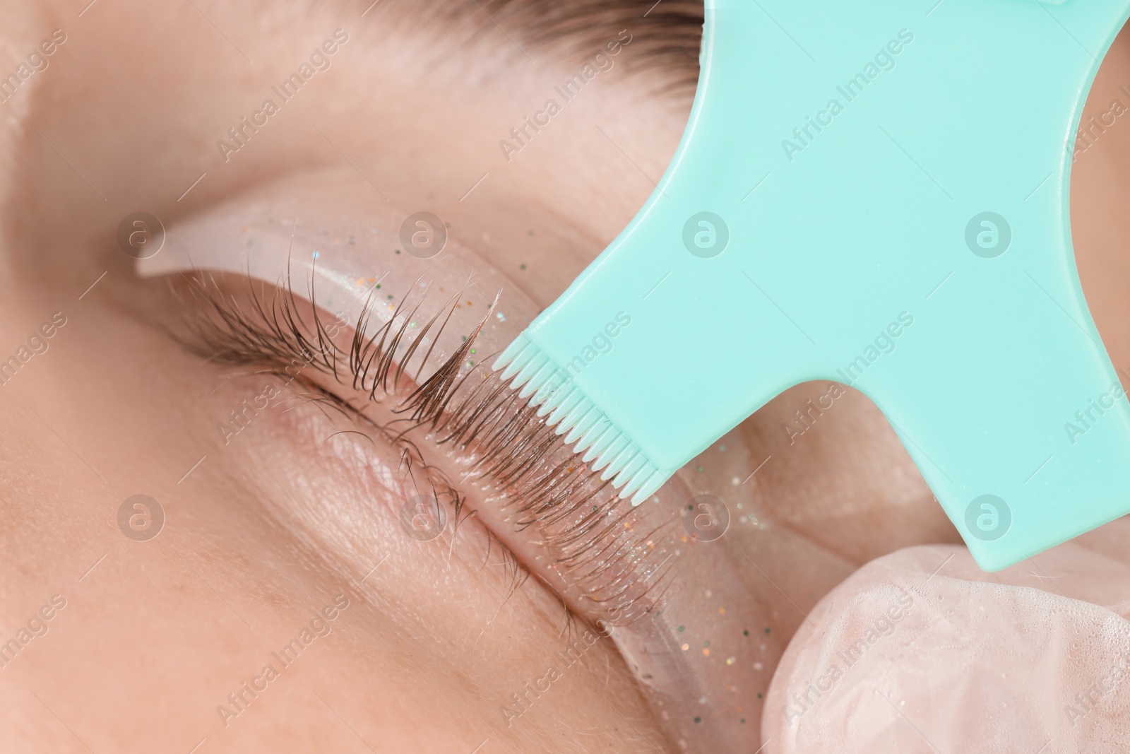 Photo of Eyelash lamination procedure. Esthetician applying adhesive on woman's lashes, closeup