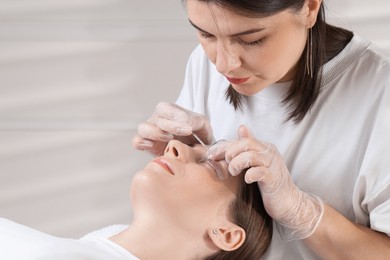 Photo of Eyelash lamination procedure. Esthetician sticking woman's lashes to pad in beauty salon, closeup