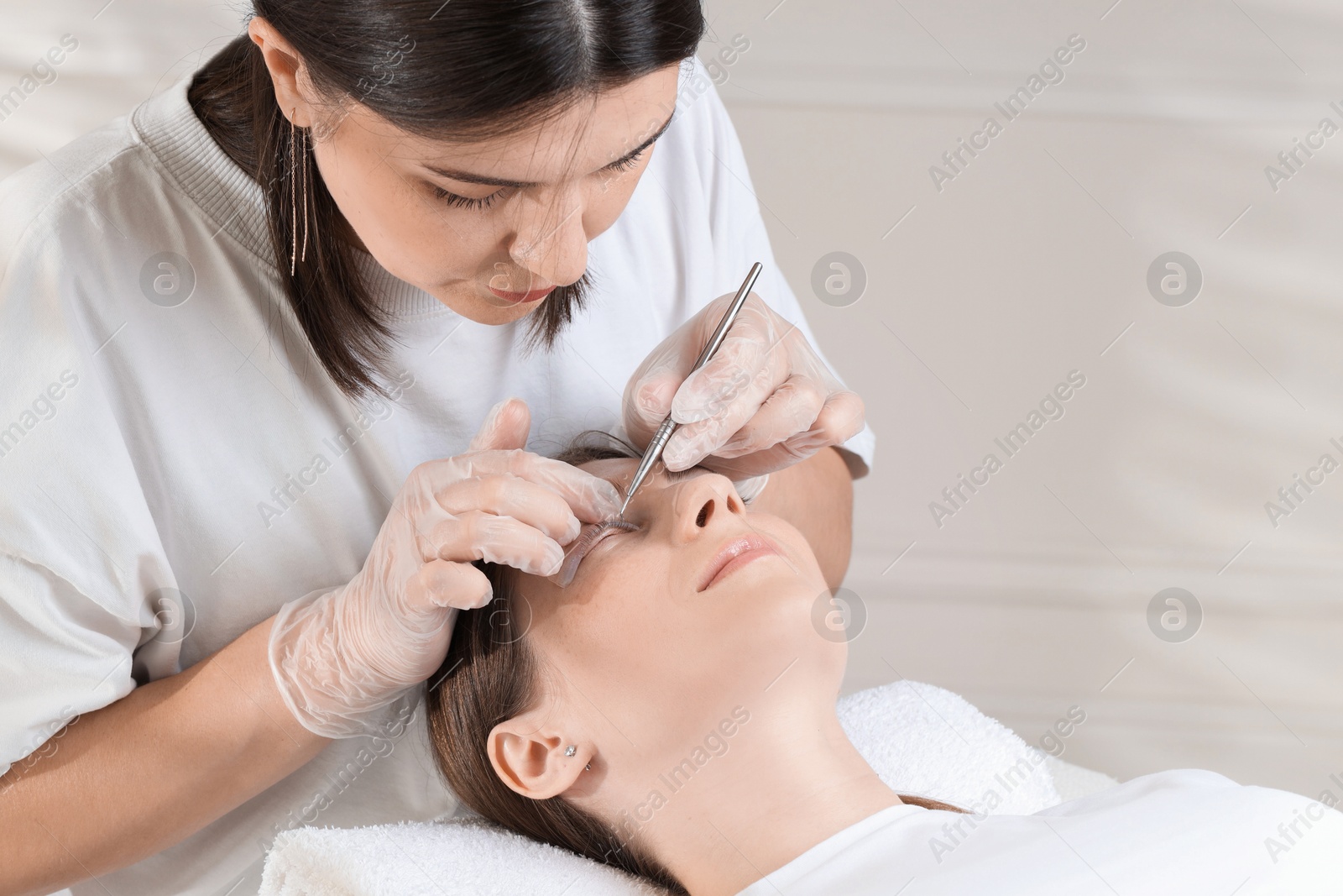 Photo of Eyelash lamination procedure. Esthetician untangling woman's lashes in beauty salon, closeup