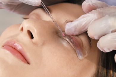 Photo of Eyelash lamination procedure. Esthetician sticking woman's lashes to pad in beauty salon, closeup