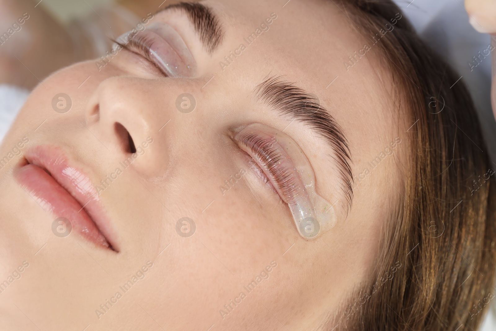 Photo of Woman undergoing eyelash laminating procedure in beauty salon, closeup