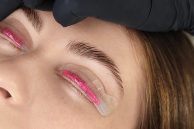 Woman undergoing eyelash laminating procedure in beauty salon, closeup