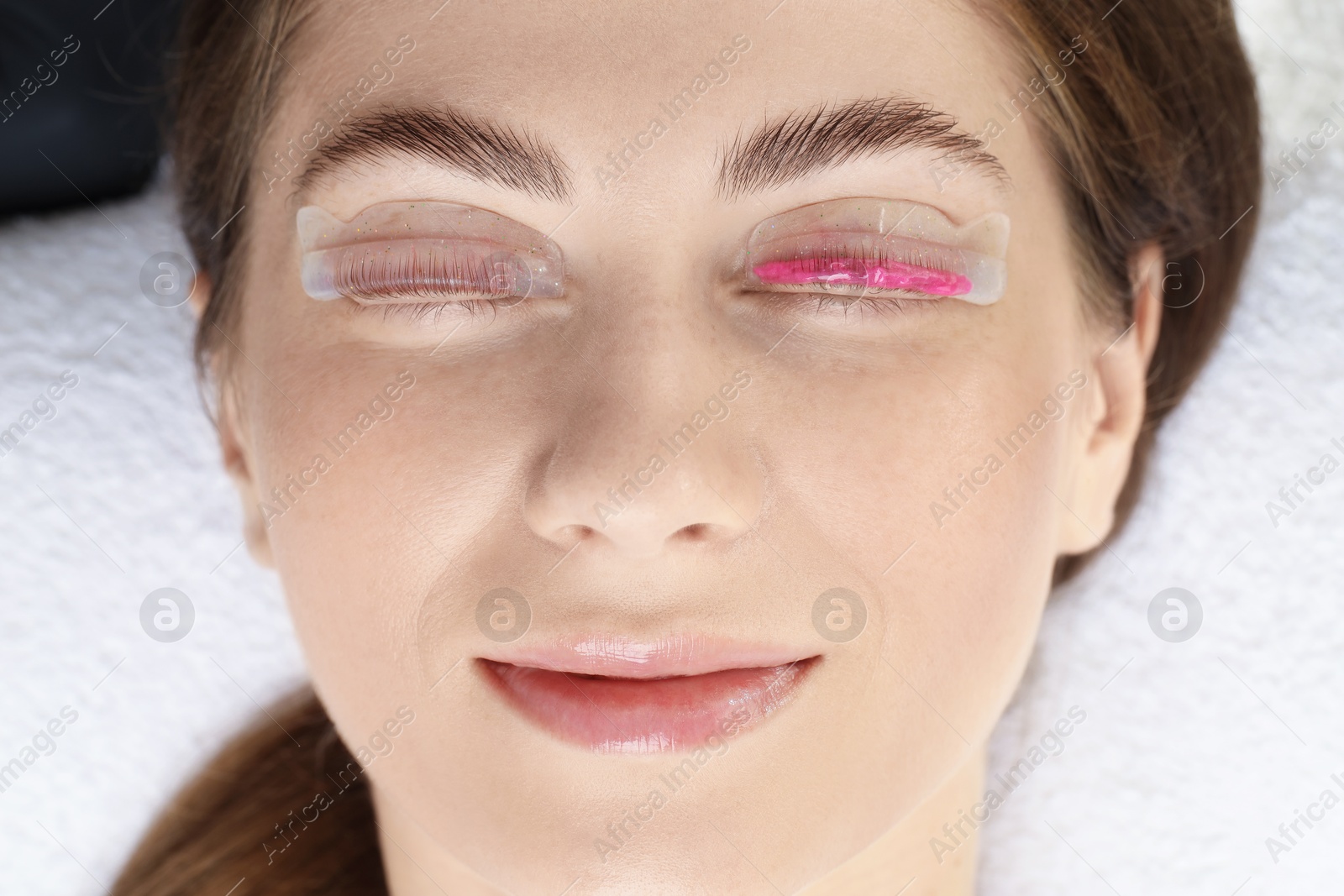 Photo of Woman undergoing eyelash laminating procedure in beauty salon, closeup