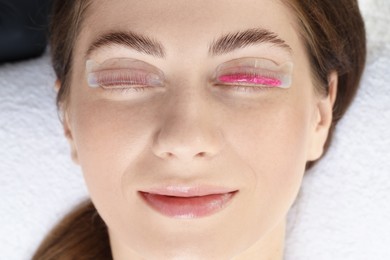 Woman undergoing eyelash laminating procedure in beauty salon, closeup