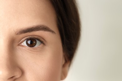 Woman with beautiful eyes on light background, closeup