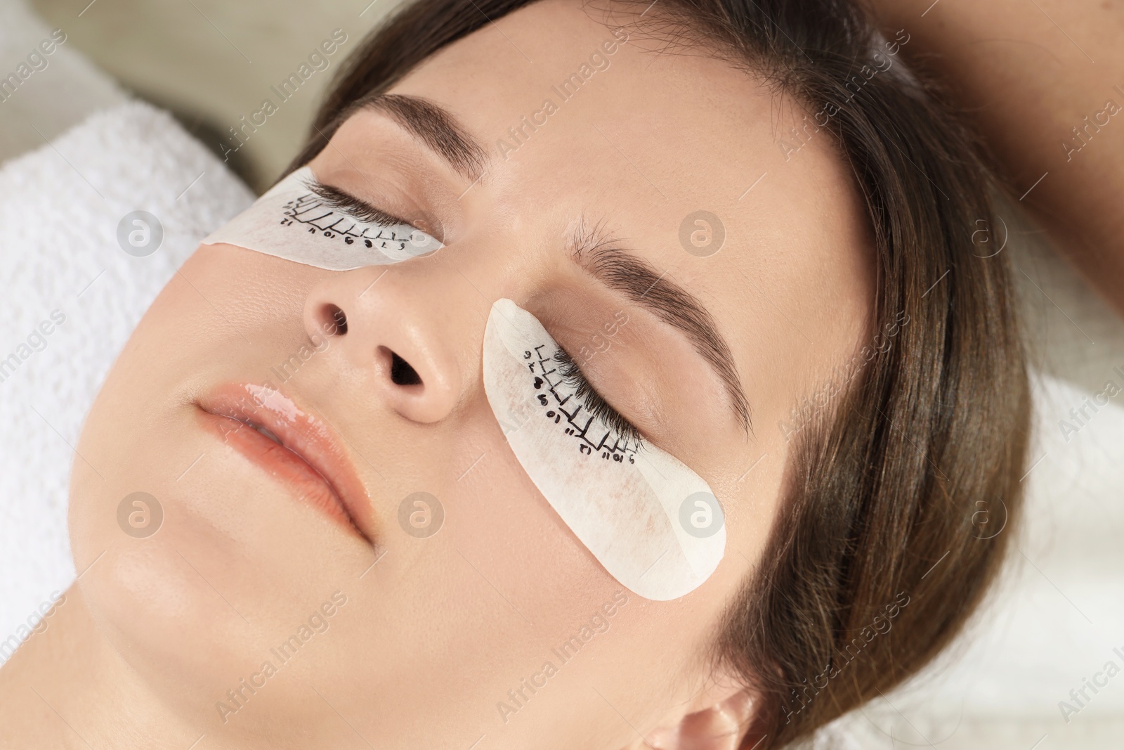 Photo of Woman with under eye patches mapped for lash extensions procedure in beauty salon, closeup