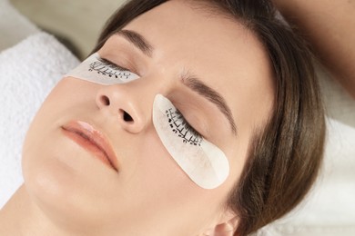 Photo of Woman with under eye patches mapped for lash extensions procedure in beauty salon, closeup