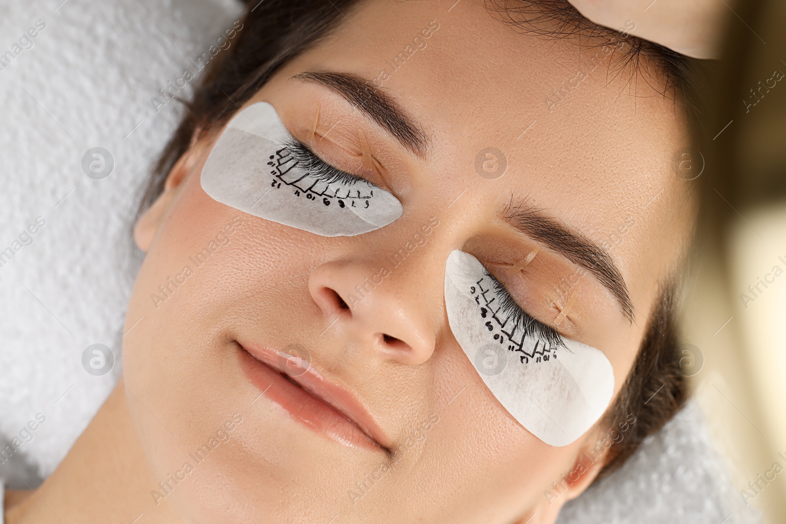 Photo of Woman with under eye patches mapped for lash extensions procedure in beauty salon, closeup