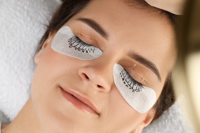 Photo of Woman with under eye patches mapped for lash extensions procedure in beauty salon, closeup