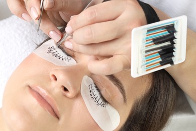 Photo of Woman undergoing lash extensions procedure in beauty salon, closeup