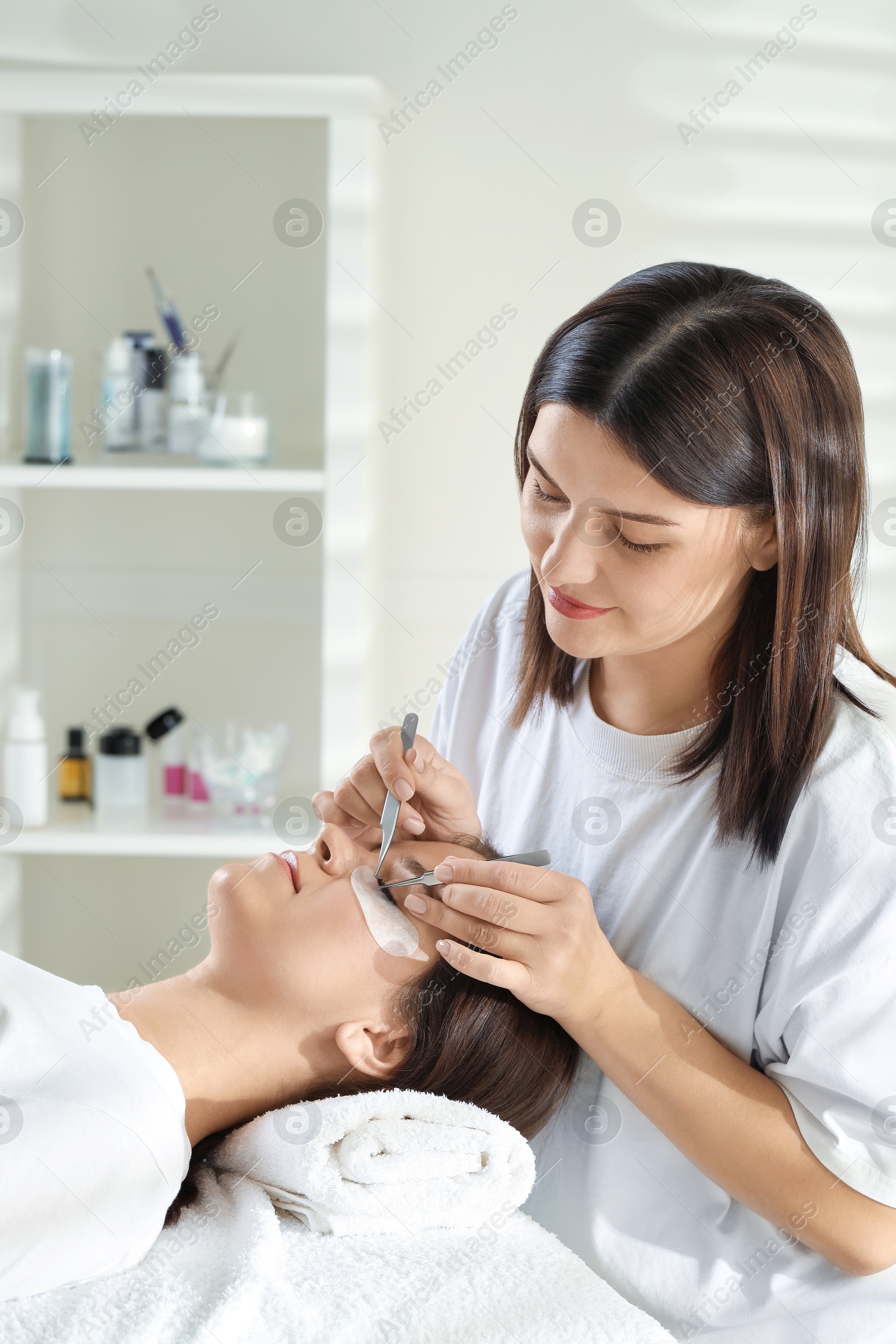 Photo of Esthetician applying lash extensions on natural ones in beauty salon