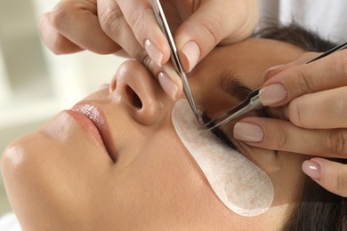 Photo of Woman undergoing lash extensions procedure in beauty salon, closeup