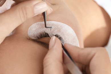 Photo of Young woman undergoing lash extensions procedure, closeup