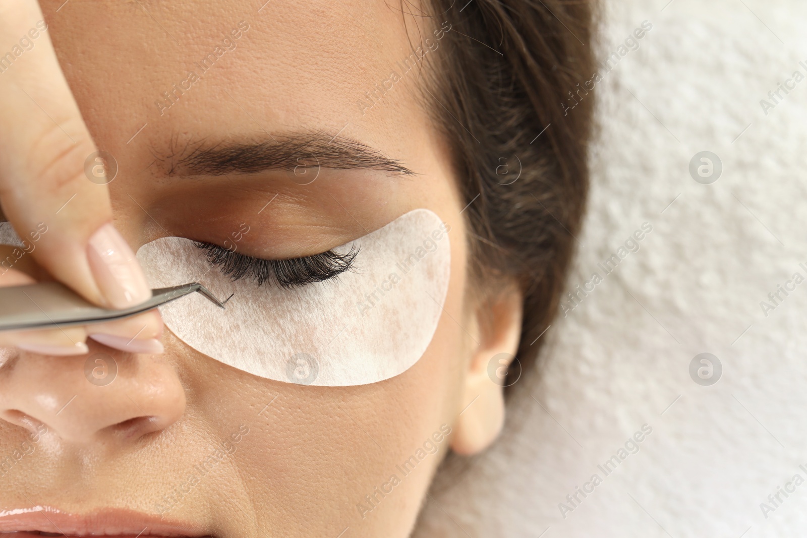 Photo of Woman undergoing lash extensions procedure in beauty salon, top view